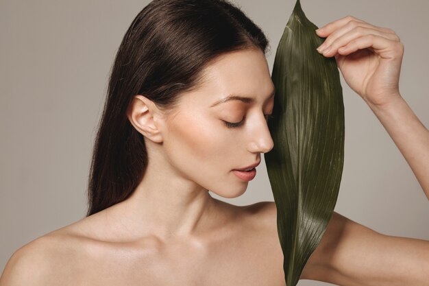 Brunette girl posing with exotic leaves