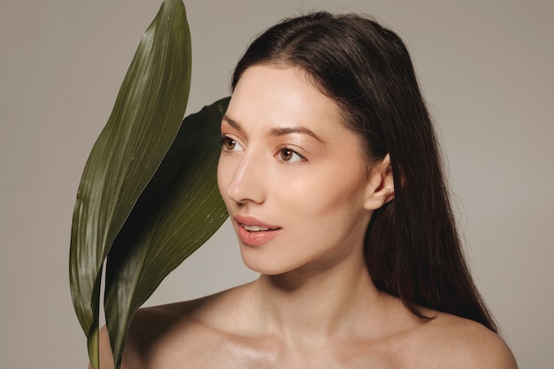 Free photo brunette girl posing with exotic leaves