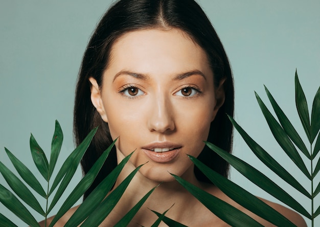 Brunette girl posing with exotic leaves