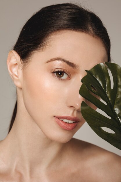 Brunette girl posing with exotic leaves