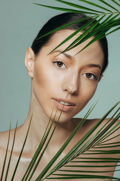 Free photo brunette girl posing with exotic leaves