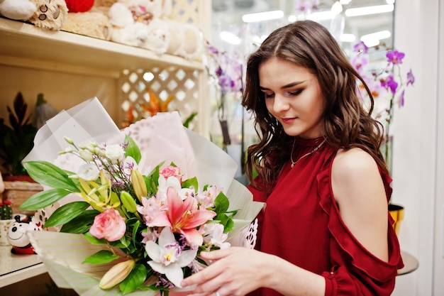Брюнетка в красном покупает цветы в цветочном магазине