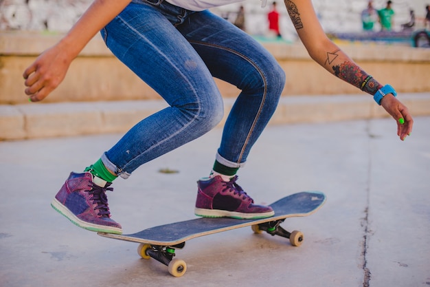 Foto gratuita ragazza bruna che guida skateboard accovacciato