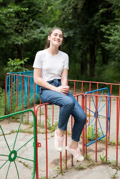 Free photo brunette girl sitting on colorful fence