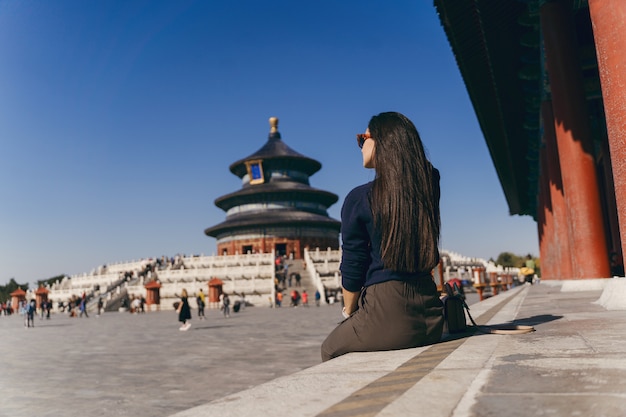 中国の天の寺院で階段に座っているブルネットの少女