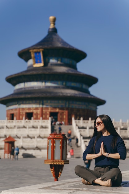 中国の天の寺院で階段に座っているブルネットの少女
