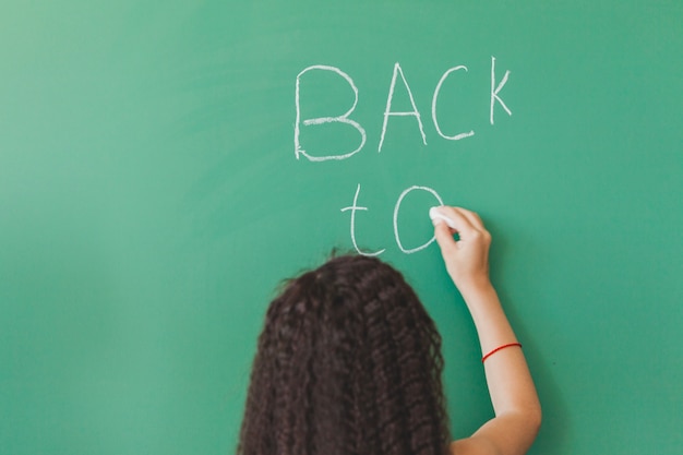 Free photo brunette girl standing at chalkboard writing