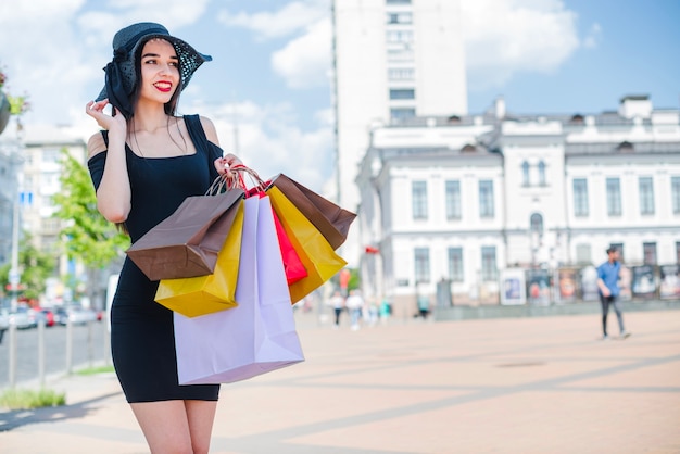 Brunette girl standing on street holding bags