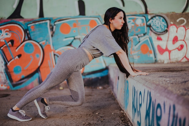 Brunette girl stretching outside leaning on hands