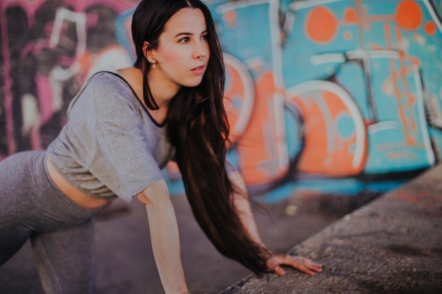 Brunette girl stretching outside leaning on hands