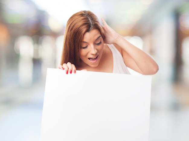 brunette girl with amazed face holding blank board