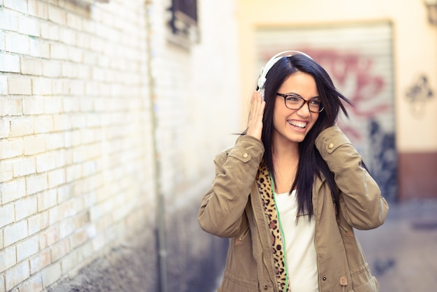 Brunette girl with glasses listening to music with headphones