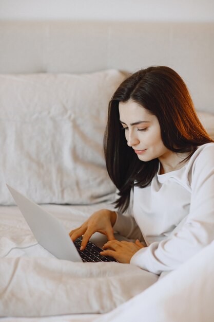 Brunette at home. Girl in a white pajamas.