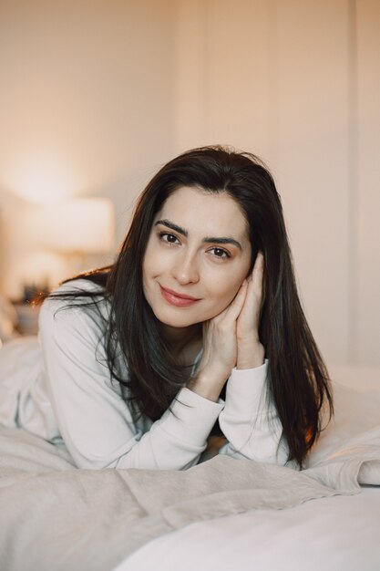 Brunette at home. Girl in a white pajamas.