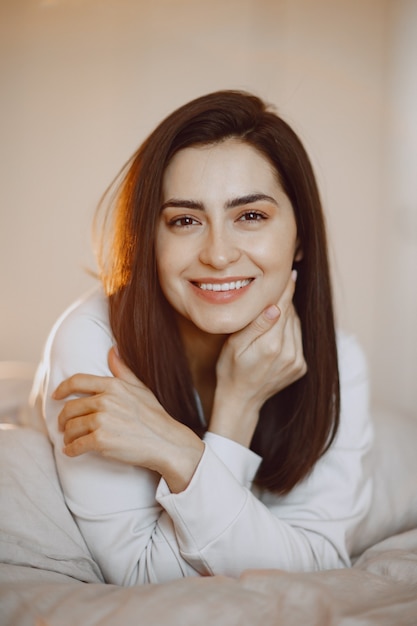 Brunette at home. Girl in a white pajamas.