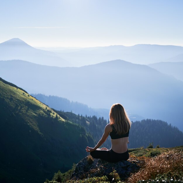 Брюнетка медитирует в позе лотоса в горах