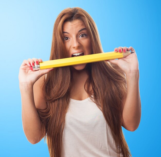 큰 노란 연필 물고 갈색 머리 아가씨.
