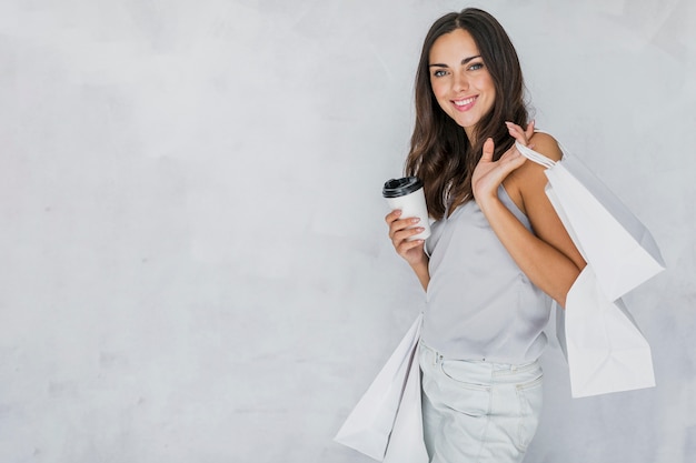 Free photo brunette lady in undershirt with shopping nets and coffee