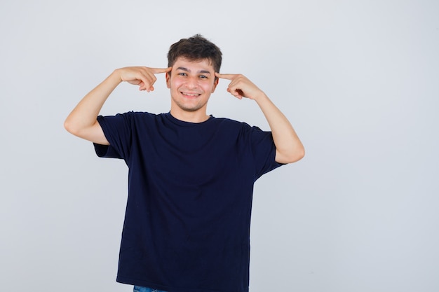 Tシャツで寺院に指を持って陽気に見えるブルネットの男、正面図。