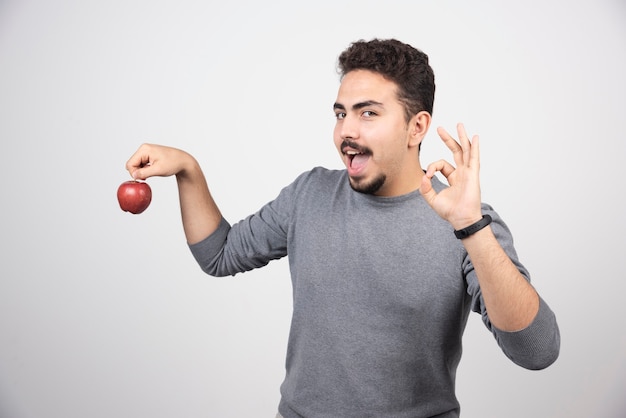 灰色の上に赤いリンゴを保持しているブルネットの男。
