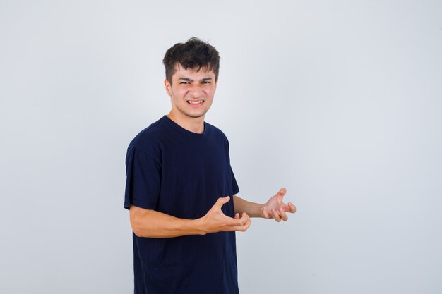 Brunette man keeping hands in aggressive manner in t-shirt and looking stressed , front view.