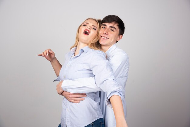 Brunette man model hugging blonde woman on gray background