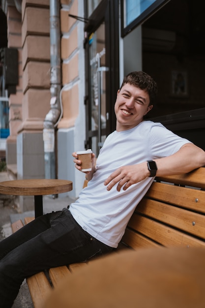 Brunette man in street cafe drinks coffee.