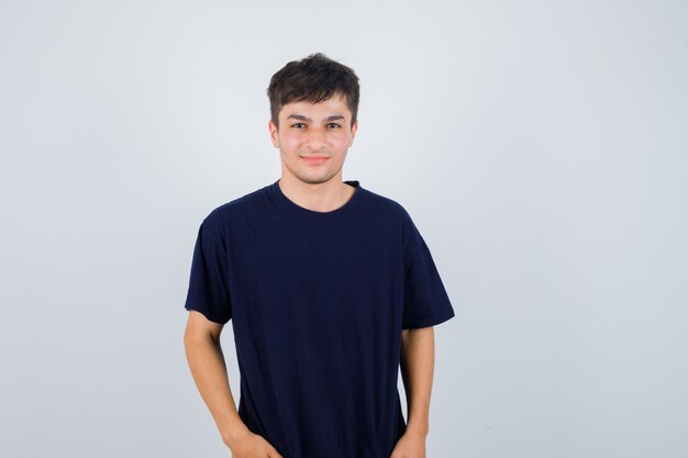 Brunette man in t-shirt posing while looking at camera and looking pleased , front view.