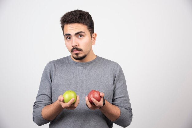 Brunette man with apples posing on gray.