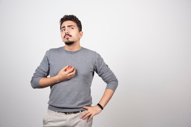 灰色の上に立っている赤いリンゴとブルネットの男。