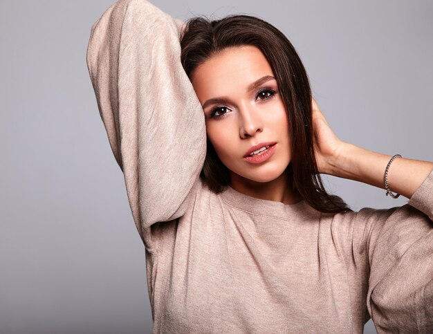 brunette model in casual beige warm sweater clothes on gray