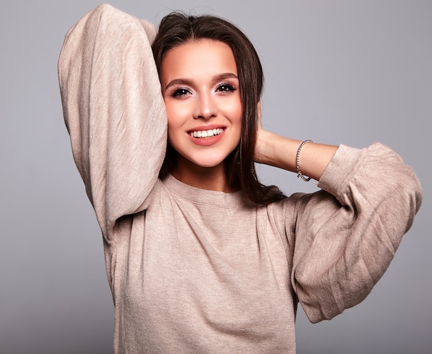 brunette model in casual beige warm sweater clothes on gray