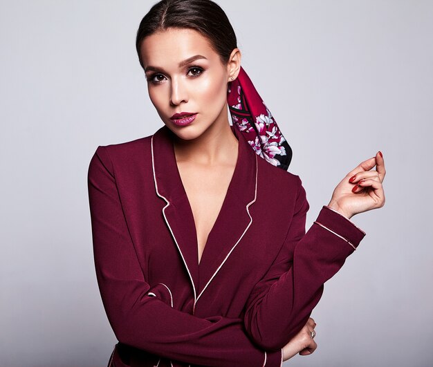 brunette model in red suit with evening makeup on gray