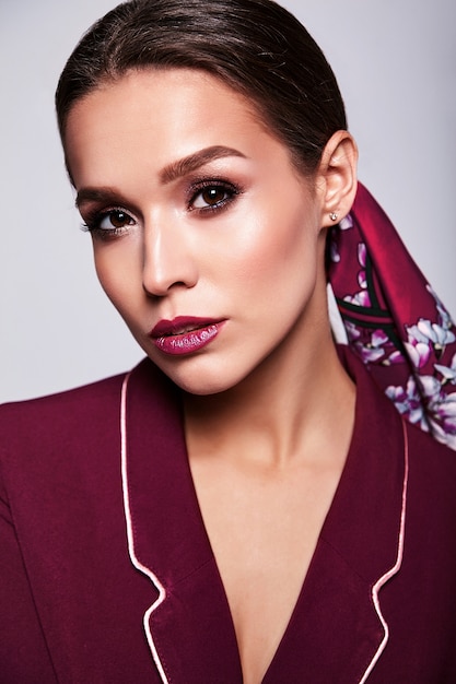 brunette model in red suit with evening makeup on gray