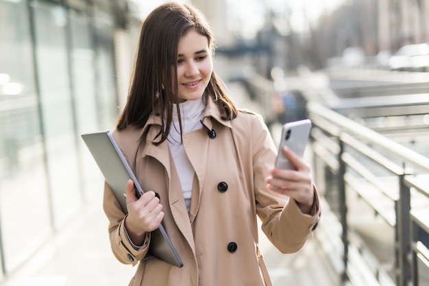 Brunette model with laptop in her hands have a videocall on her phone