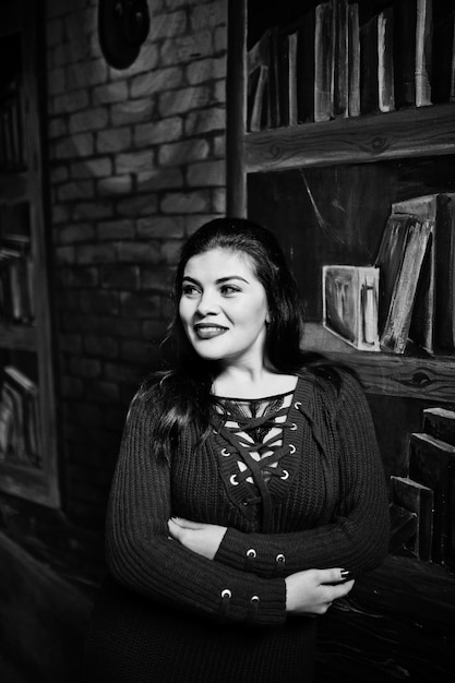 Free photo brunette plus size model against wall like library