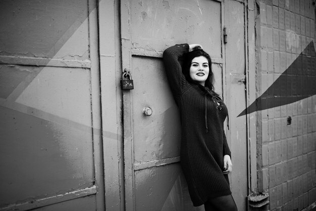 Brunette plus size model at red against colored wall