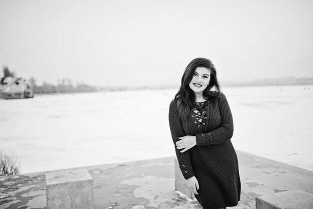 Brunette plus size model at red against frozen lake on winter day