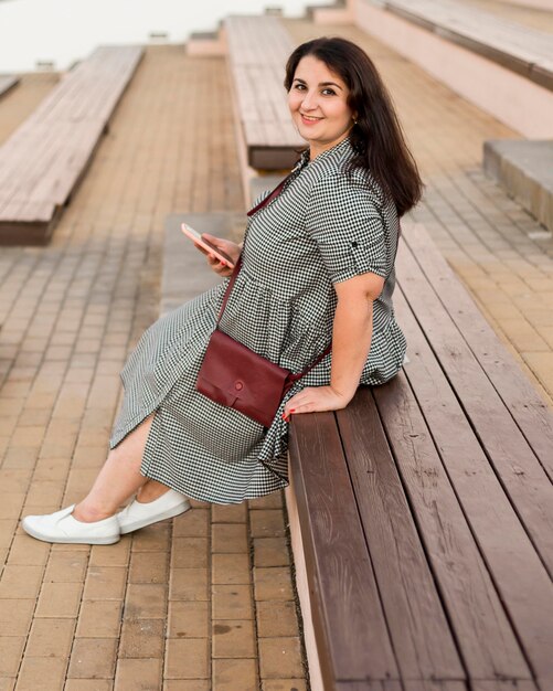 Brunette smiley woman holding her smartphone