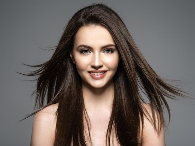 Brunette smiling woman with beauty long brown hair. Fashion model with long straight hair. Fashion model posing . Pretty woman with long straight brown hair.
