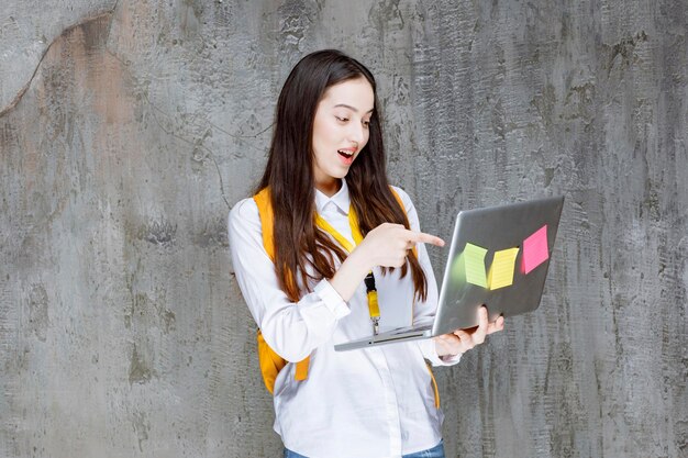 Brunette student standing and working on laptop. High quality photo