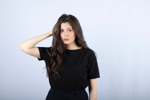 brunette woman in black top looking over white wall.