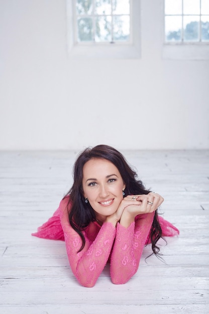 Free photo brunette woman in a cherry dress lying on the floor.