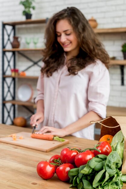 Free photo brunette woman cutting carrots