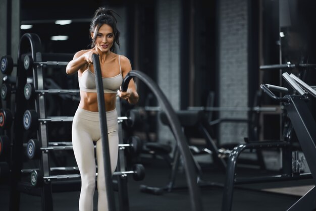 Brunette woman doing battle rope training.