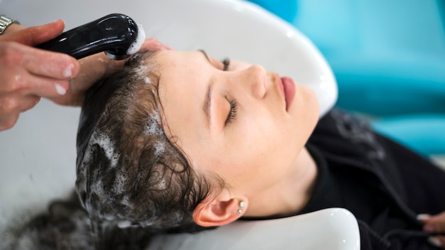 Free photo brunette woman getting her hair washed