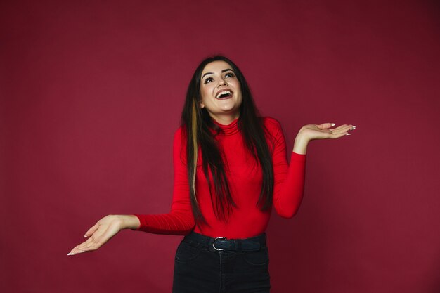 Brunette woman has happy look and holds her hands in the sides