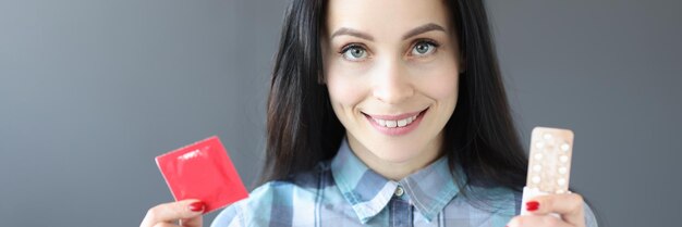 Brunette woman holding condom and birth control pills