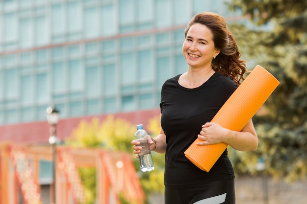 Brunette woman holding a yoga mat with copy space