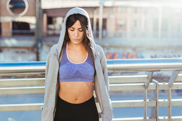 Foto gratuita donna bruna in hoodie in piedi fuori